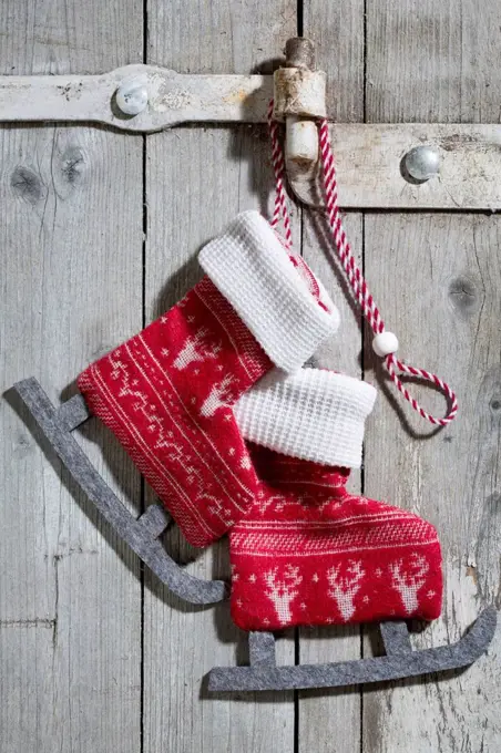 Pair of decorative textile ice skates hanging on wooden door