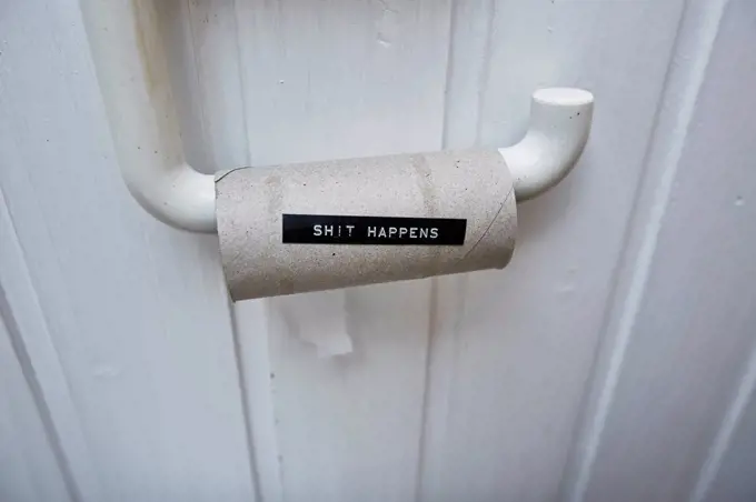 Empty toilet paper roll with message shit happens