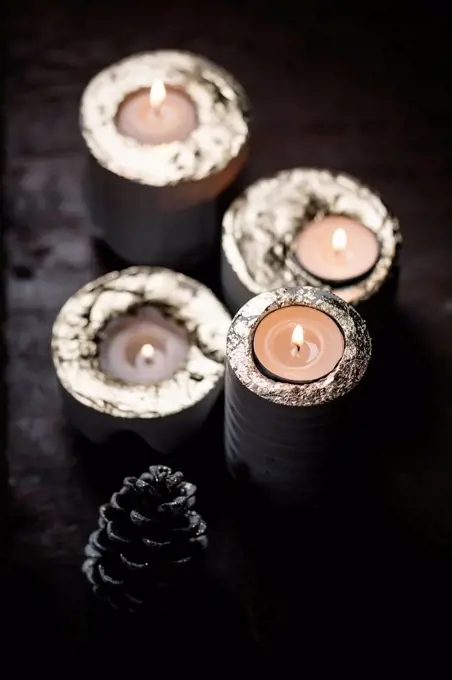 Four lighted advent candles and a fir cone