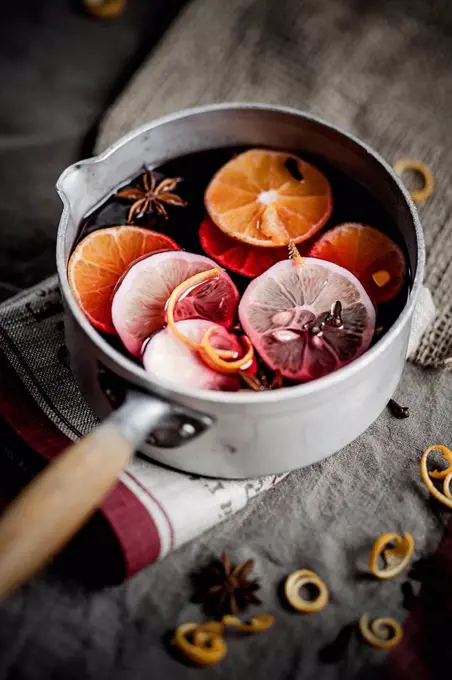 Casserole with mulled wine, slices of lemons and oranges and spices