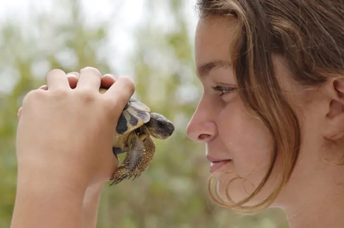 Girl (10-13) holding turtle, profile, close-up
