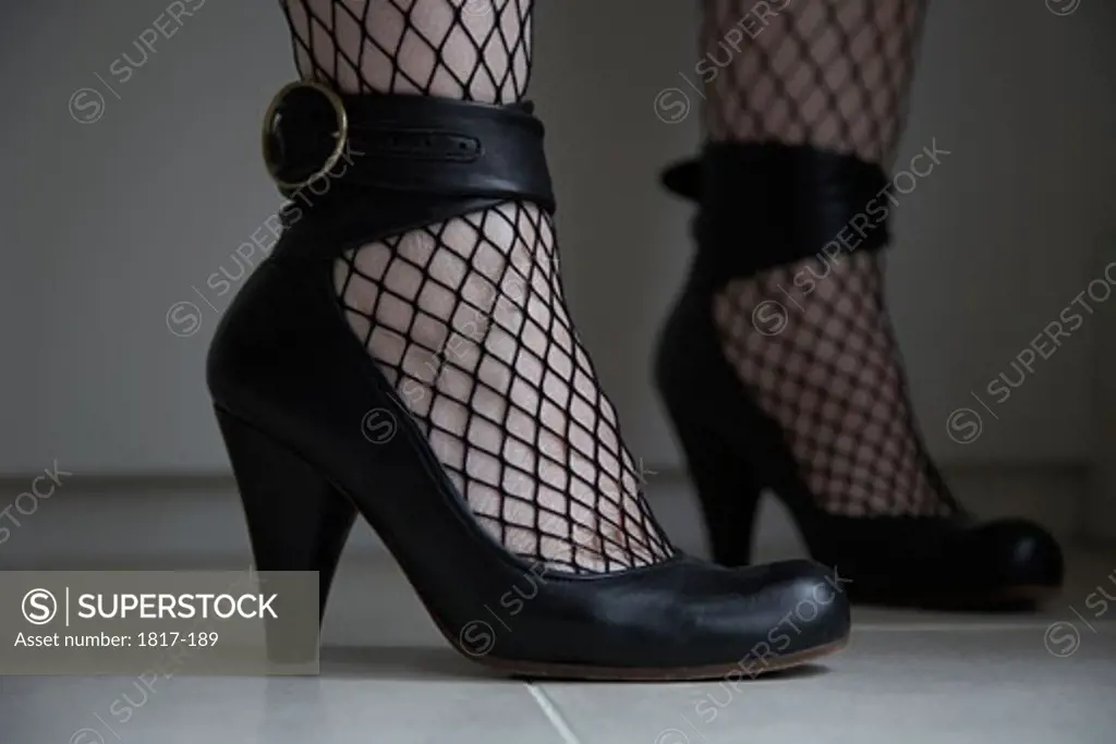 Womans feet with high heeled shoes and fishnet stockings
