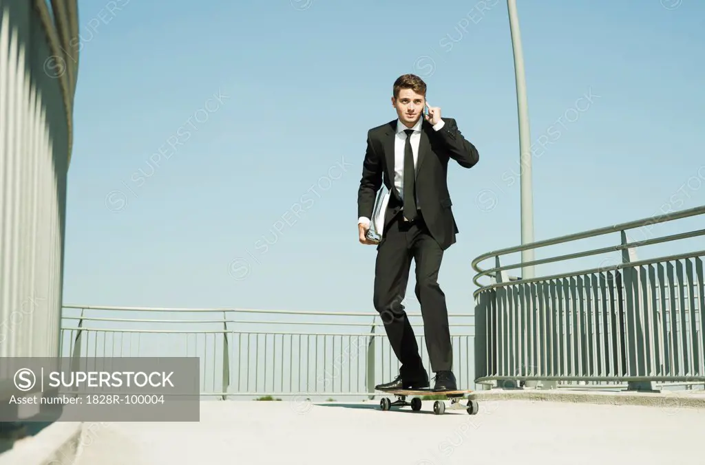 Businessman using Cell Phone while Skateboarding, Mannheim, Baden-Wurttemberg, Germany. 09/04/2013