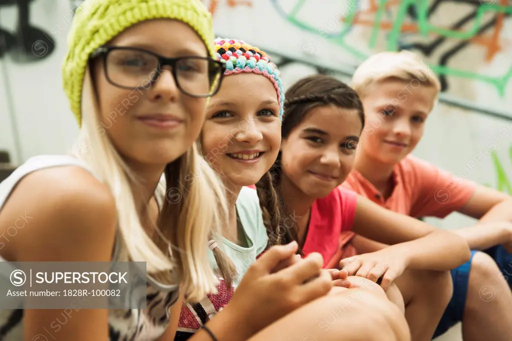 Close-up of group of children sitting on stairs outdoors, looking at camera, Germany. 08/31/2013