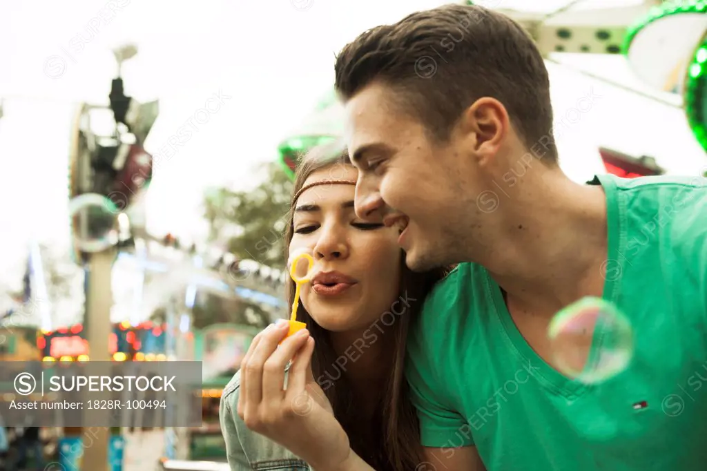 Close-up portrait of young couple blowing bubbles at amusement park, Germany. 10/12/2013