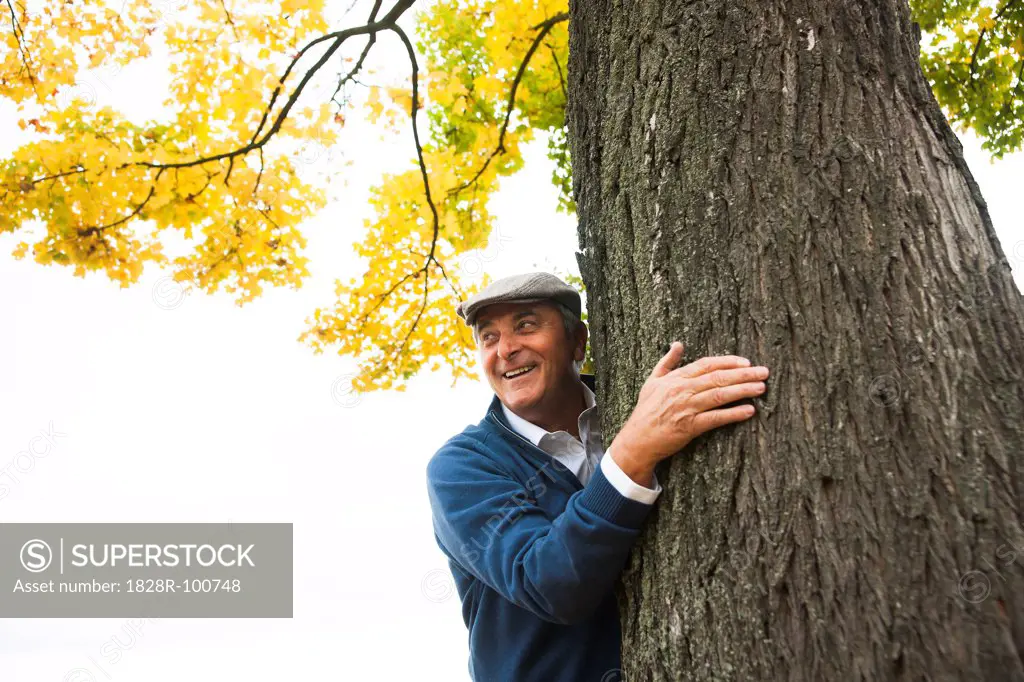 Senior Man Standing behind Tree, Mannheim, Baden-Wurttemberg, Germany. 10/16/2013