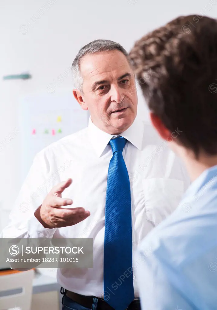 Businessman explaining work to apprentice in office, Germany. 10/27/2013