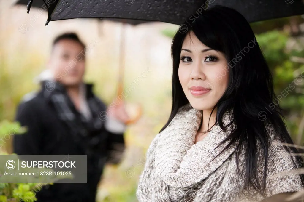 Close-up portrait of woman under umbrella with man in background, Ontario, Canada. 10/25/2011