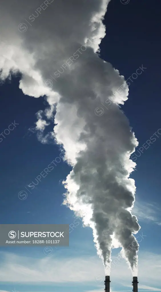 Close-up of industrial smoke stacks with steam billowing into blue sky, Toronto, Ontario, Canada. 01/22/2014