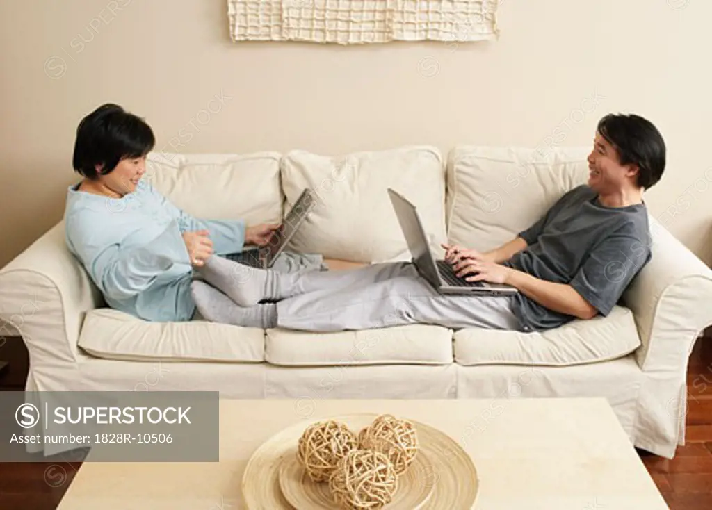 Couple Using Laptops on Sofa   