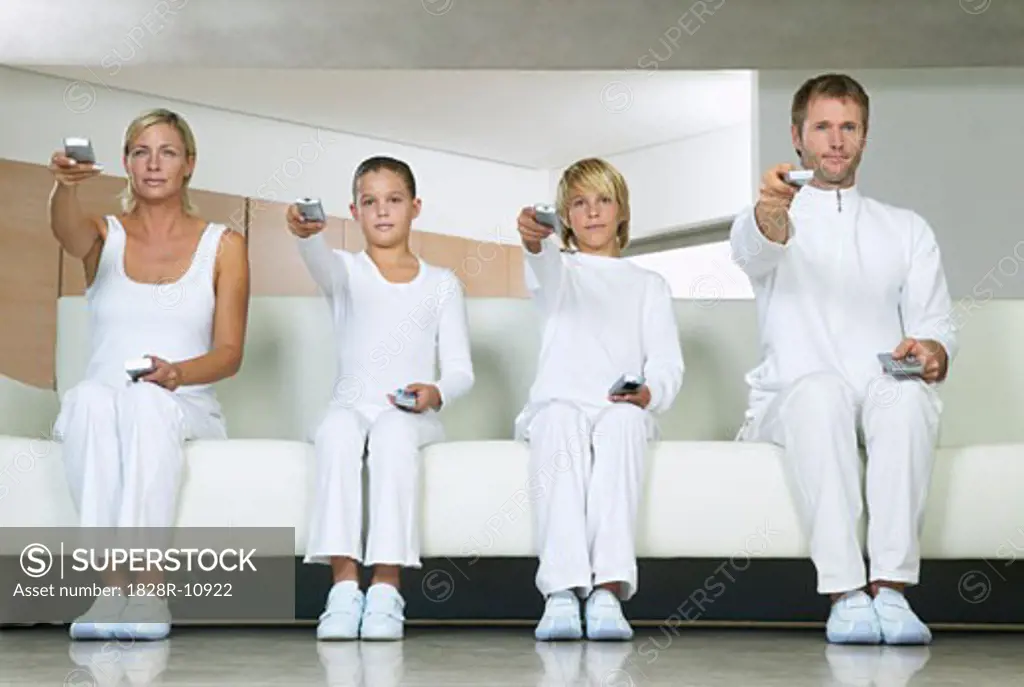 Portrait of Family Sitting on Sofa, Using Remote Controls   