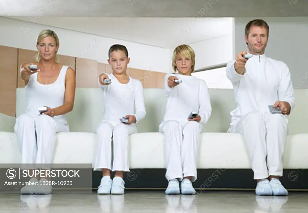 Portrait of Family Sitting on Sofa, Using Remote Controls   