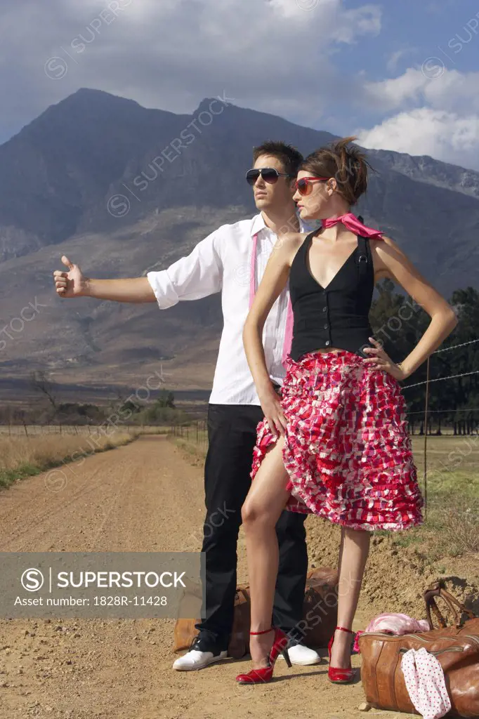 Couple Hitchhiking On Country Road   