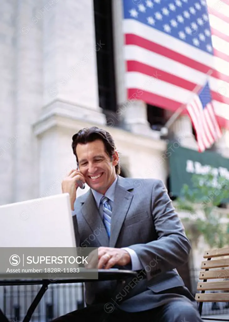 Businessman with Laptop Computer by American Flag   