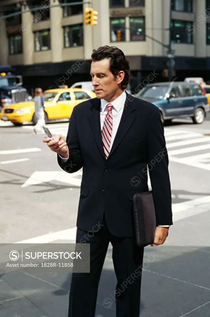 Businessman using Cellular Phone on Sidewalk   