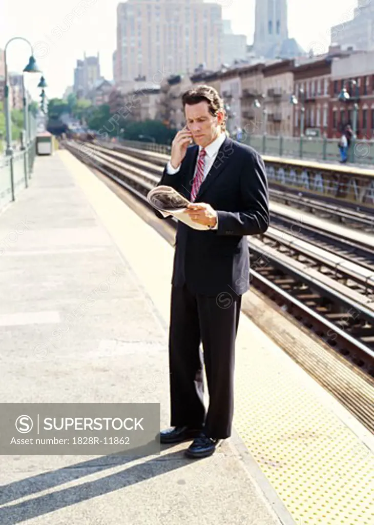 Man with Cellular Phone and Newspaper on Train Platform   