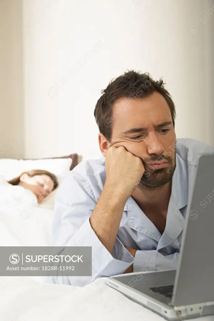 Man Using Laptop in Bed   
