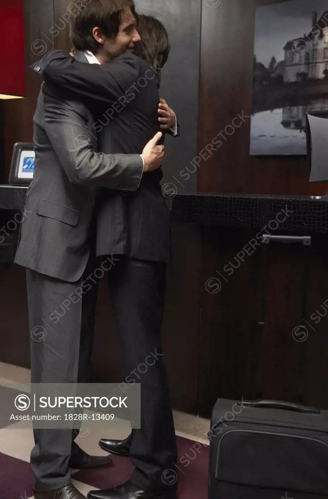 Businessmen Hugging in Hotel Lobby   