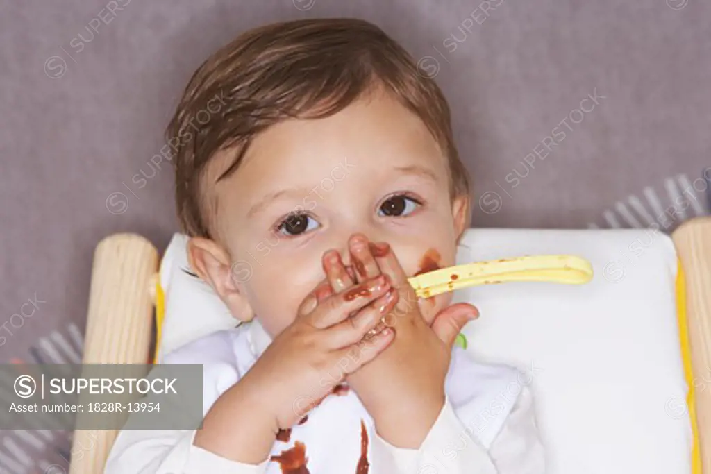 Baby Eating Pudding in High Chair   