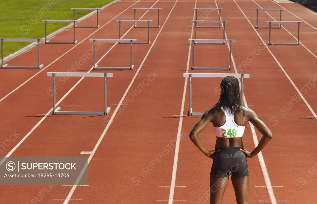 Back View of Woman Standing in Front of Hurdles on Track   