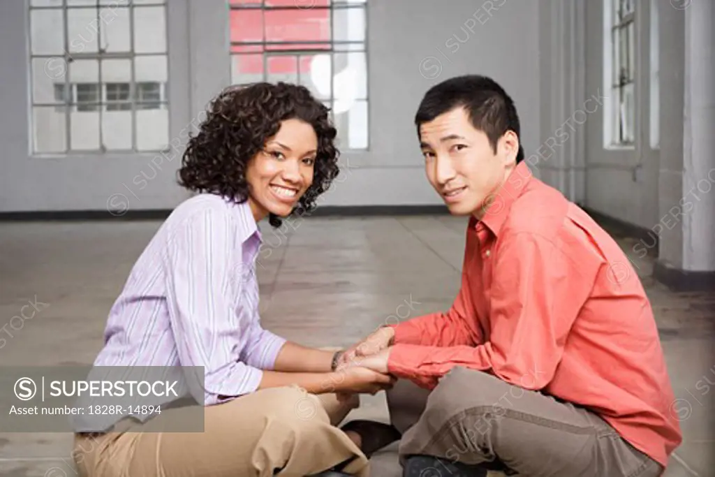 Couple Sitting on Floor Holding Hands   