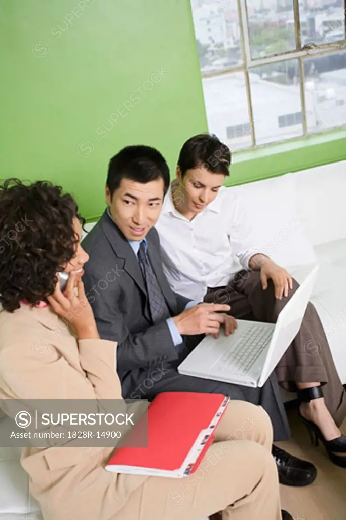 Business People Sitting on Sofa using Laptop and Cell Phone   