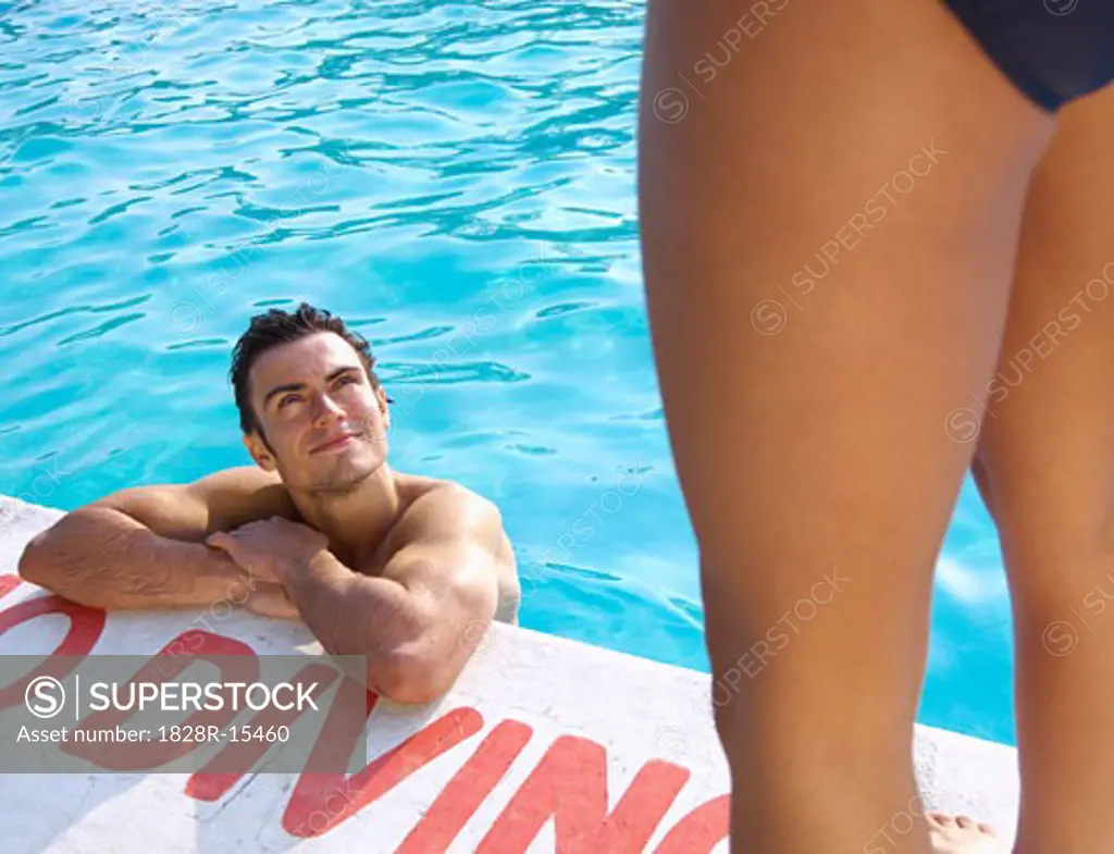 Man in Swimming Pool Looking up at Woman   
