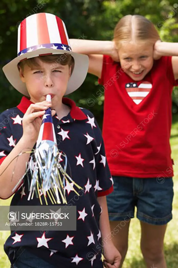 Portrait of Boy Wearing Stars and Stripes Top and Hat, Blowing Noisemaker Horn, Girl Watching   