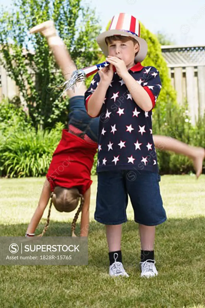 Boy Wearing Stars and Stripes Top and Hat, Girl doing Cartwheel in Background   