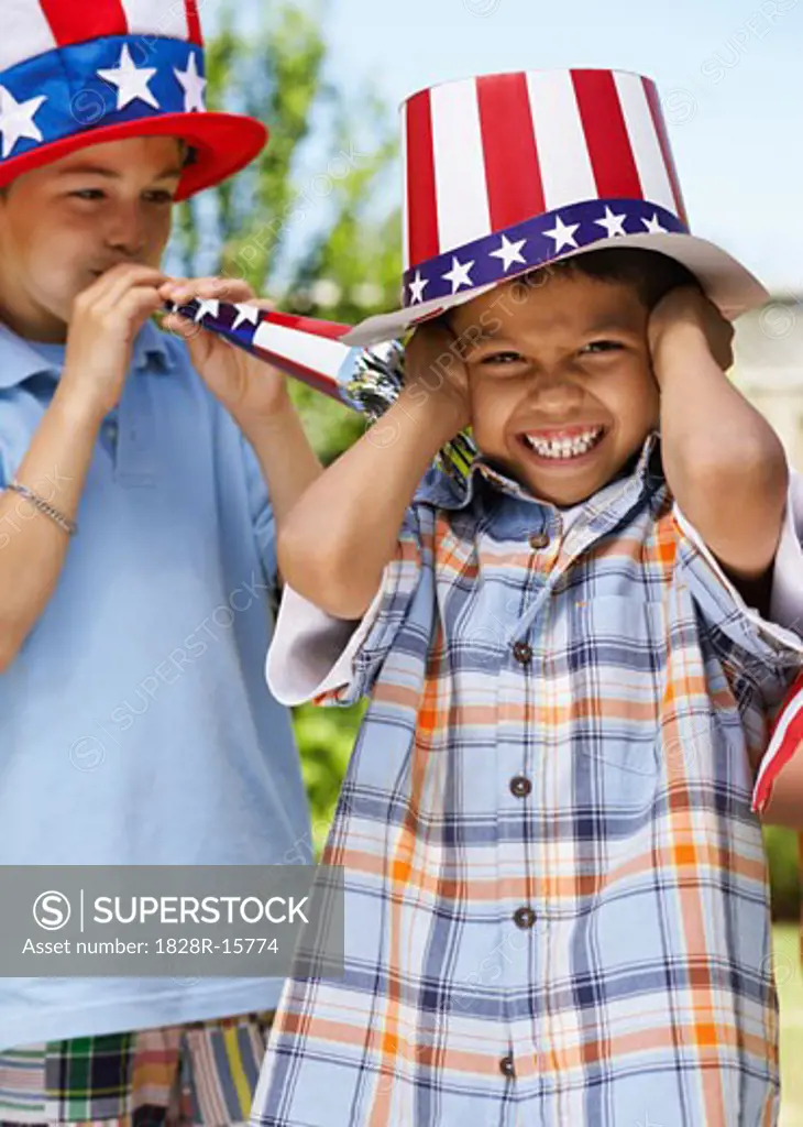 Portrait of Boy Wearing Stars and Stripes Hat with Boy Blowing Noisemaker Horn   
