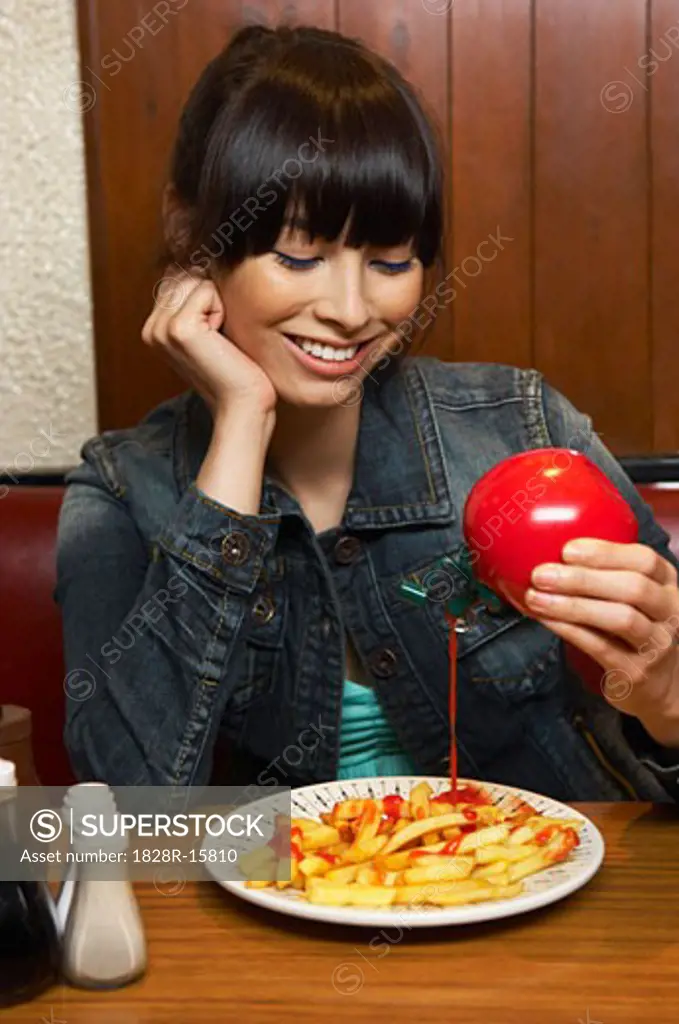 Woman Pouring Ketchup on French Fries   