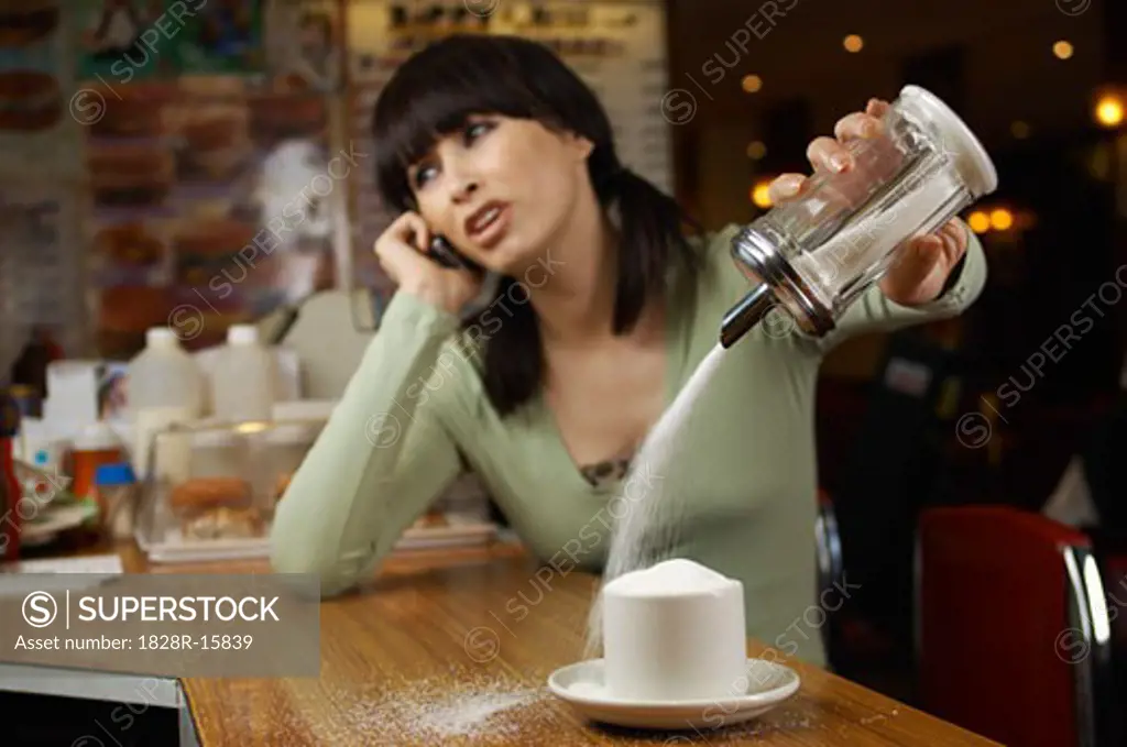 Woman Distracted by Phone Call, Filling Cup with Sugar   