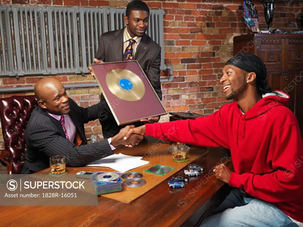 Record Executives Presenting Gold Record to Hip Hop Artist   