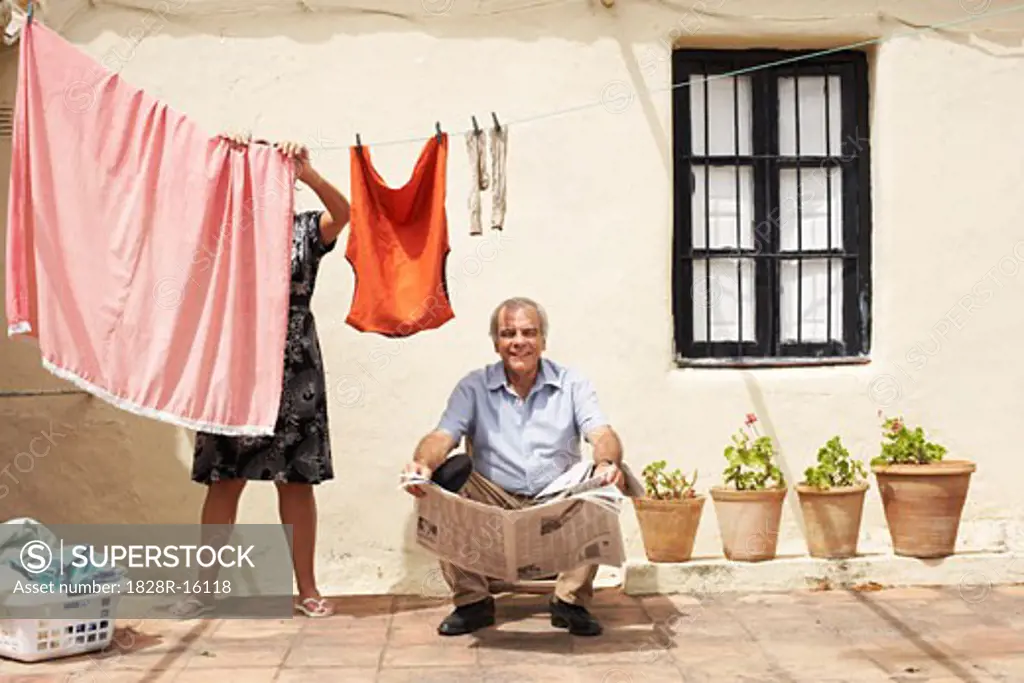 Couple on Patio with Newspaper and Laundry   