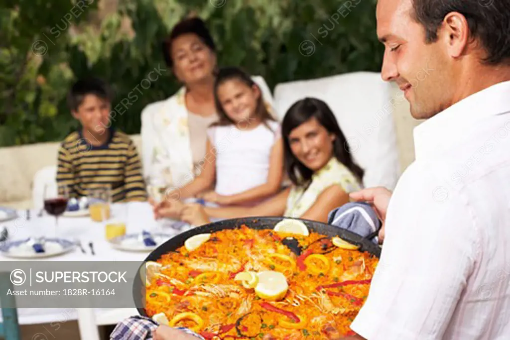 Man Serving Family Meal Outdoors   