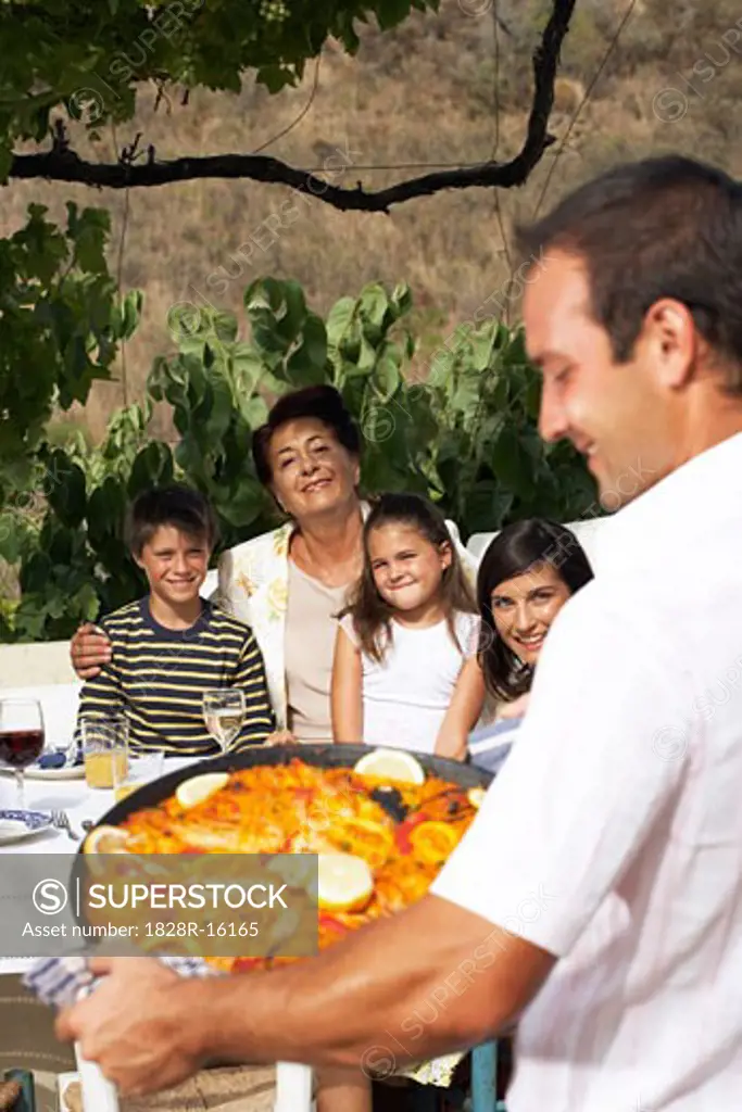 Man Serving Family Meal Outdoors   