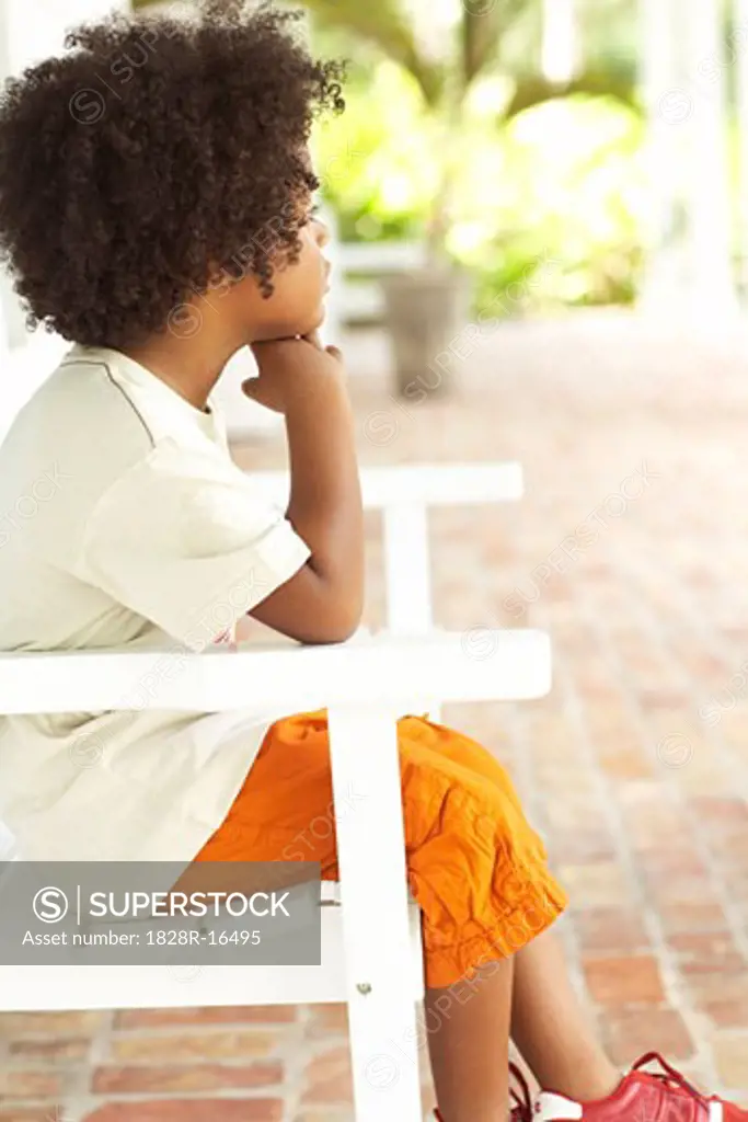 Boy Sitting in Chair Outdoors   