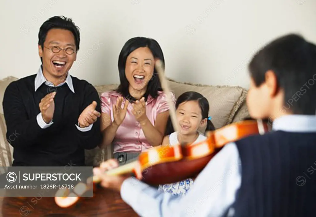 Family Watching Boy Play Violin   