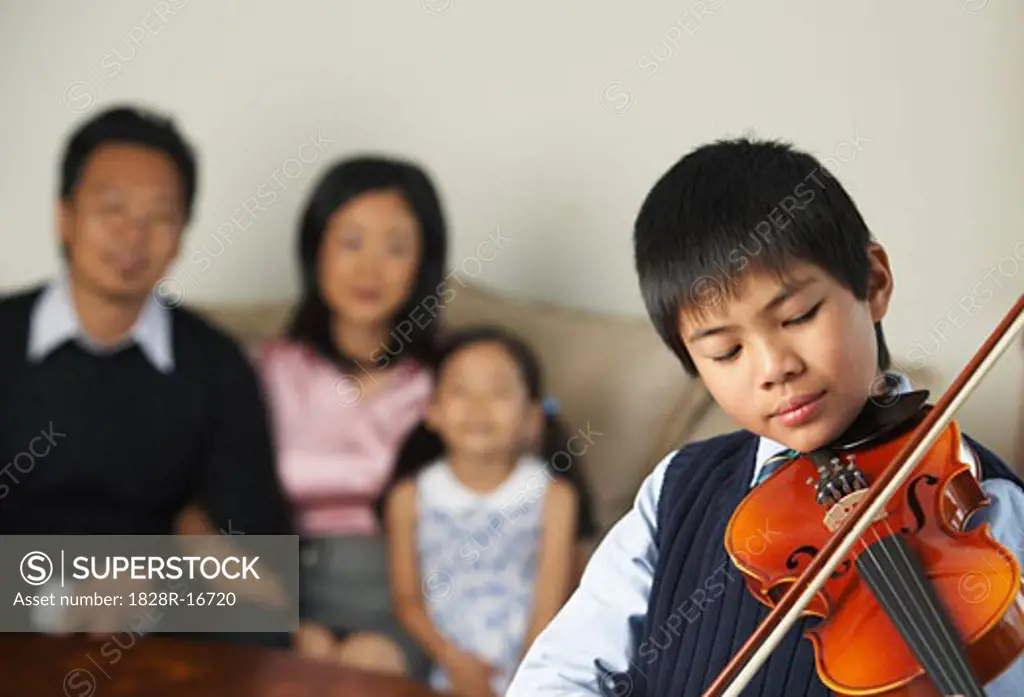 Portrait of Boy Playing Violin While Family Watches   