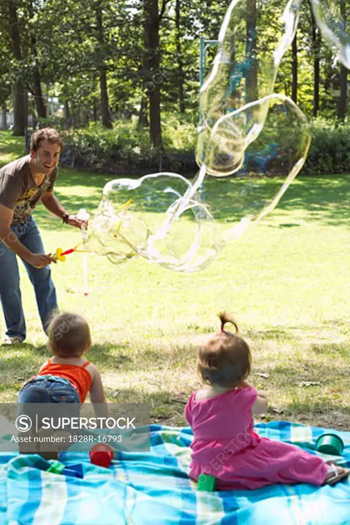 Father Blowing Bubbles while Babies Watch   