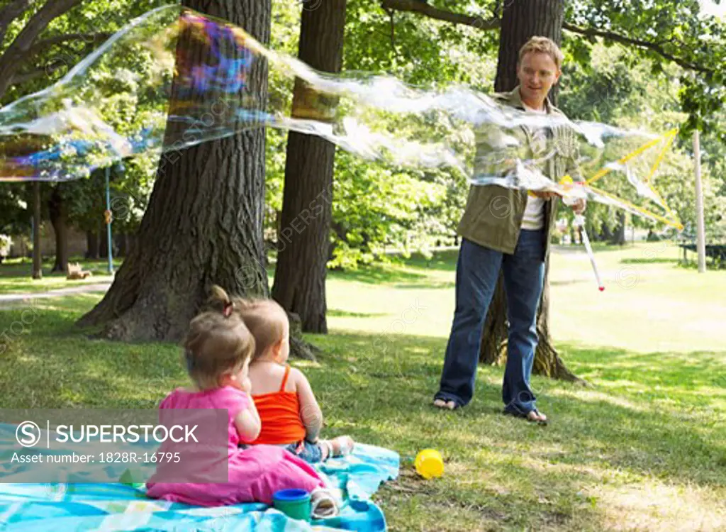 Father Blowing Bubbles while Babies Watch   