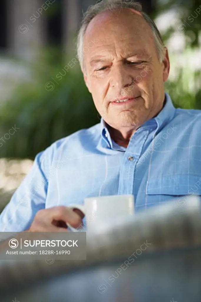 Man Reading Newspaper and Drinking Coffee   