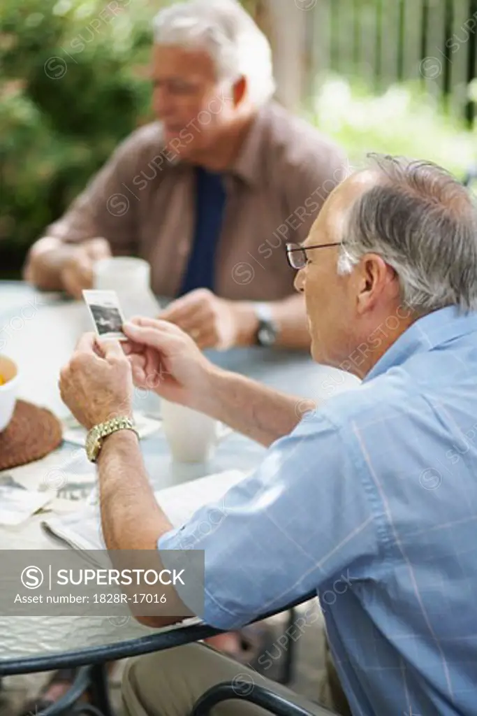 Men Sitting Outdoors Looking at Photos   