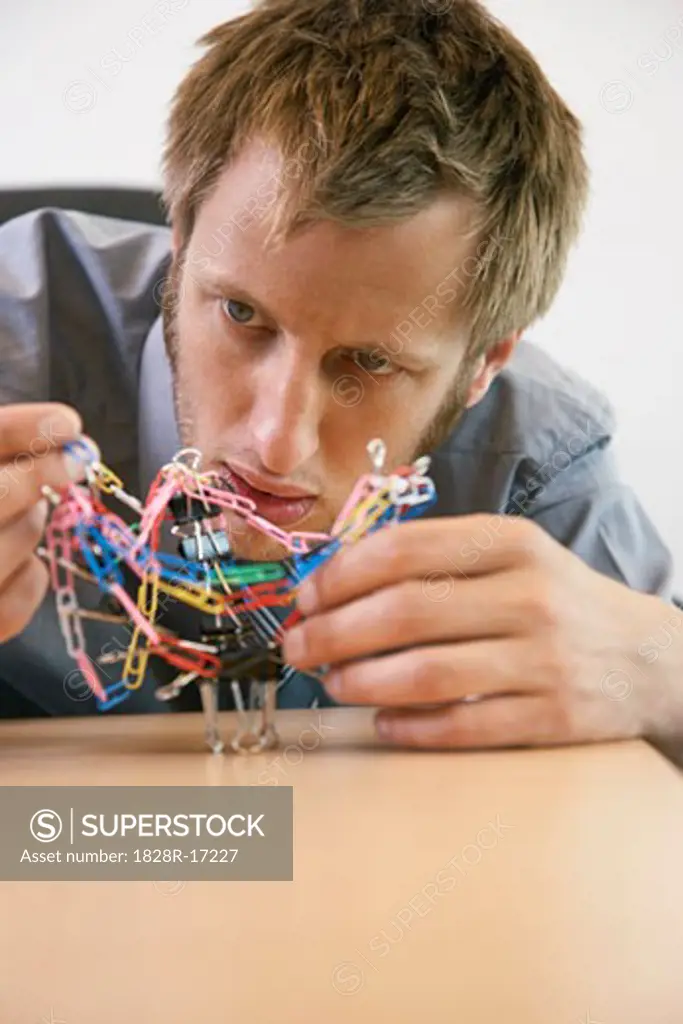 Businessman Playing with Paperclips   