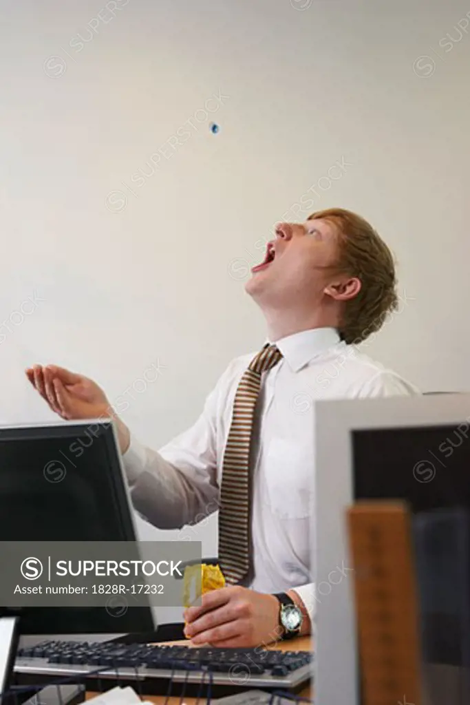 Businessman Tossing Candy into Mouth   