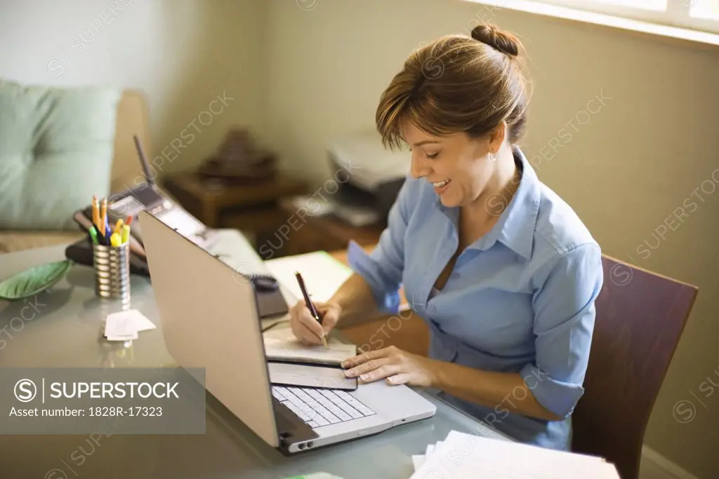 Woman Signing Cheque in Home Office   