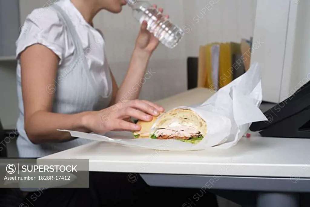 Businesswoman Eating at Desk   