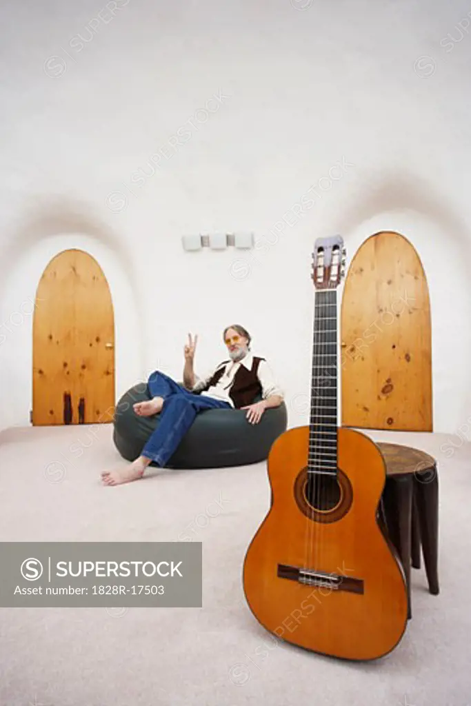 Man Sitting in Bean Bag Chair with Guitar in Foreground   