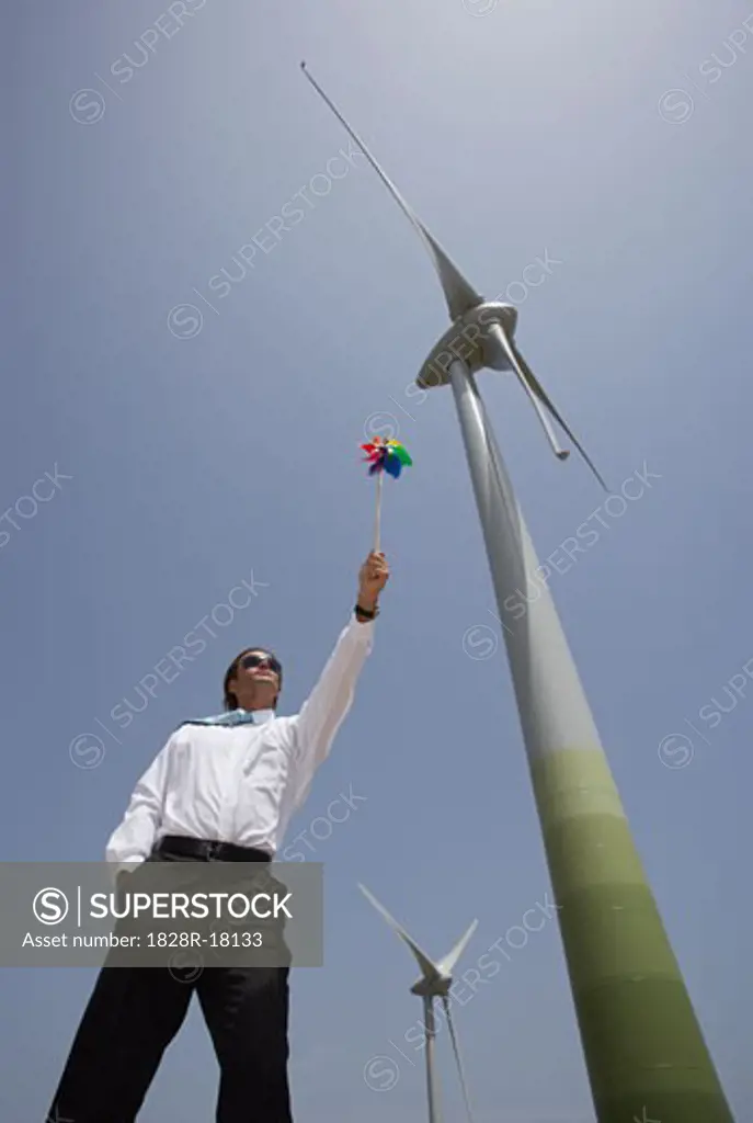 Businessman with Pinwheel by Wind Turbine   
