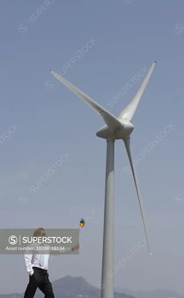 Businessman with Pinwheel by Wind Turbine   
